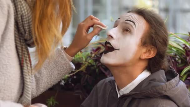 Mädchen malen Gesicht zu jungen Mann Mime mit schwarzem Bleistift — Stockvideo