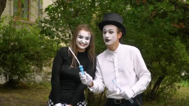 Dos jóvenes mimos divertidos soplando burbujas de jabón al aire libre en cámara lenta — Vídeos de Stock