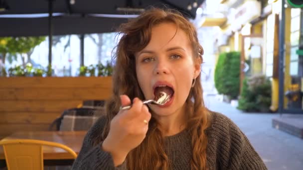 Jonge vrouw eet een chocoladetaart en drink vers sap, close-up — Stockvideo