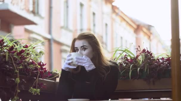 Grappige vrouwelijke mime drinken koffie in de straat cafe — Stockvideo