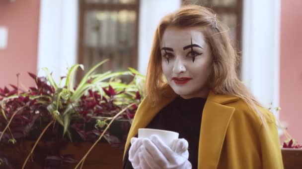 Grappige vrouwelijke mime drinken koffie in de straat cafe — Stockvideo