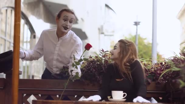 Два счастливых мима на свидании в кафе. Счастливый мужчина дарит цветок своей девушке — стоковое видео