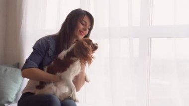 Pencerenin yanında köpeği olan bir kadın.