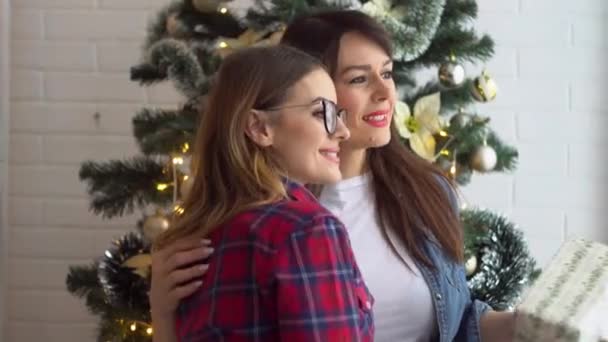 Dos mujeres felices sosteniendo regalos cerca del árbol de Navidad — Vídeo de stock