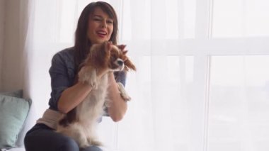 Pencerenin yanında köpeği olan bir kadın.