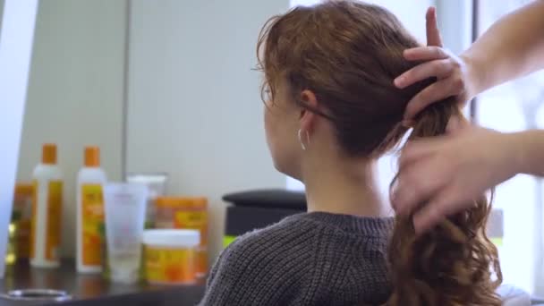 Fryzjer robi modne świąteczne fryzury na długich włosach. Tworzenie nici włosów z rąk — Wideo stockowe