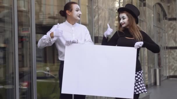 Twee mimespelers man en vrouw op straat met grote reclamebanner — Stockvideo