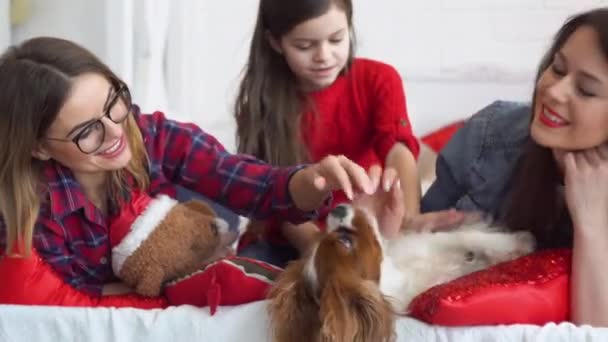 Dos mujeres felices y una niña pequeña con perro abrazándose en la cama — Vídeos de Stock