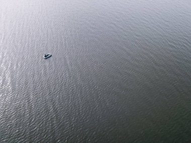 Göldeki küçük bir balıkçı teknesiyle balıkçıların üzerinden uçan bir hava aracı. Güzel bir yaz manzarası gölü. Hava görüntüsü. İnsansız hava aracı güzel bir gölün üzerinde