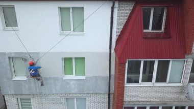 Endüstriyel tırmanışçı yeni bir binanın cephesini boyuyor.