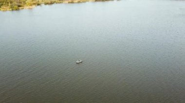Göldeki küçük bir balıkçı teknesiyle balıkçıların üzerinden uçan bir hava aracı. Güzel bir yaz manzarası gölü. Hava görüntüsü. İnsansız hava aracı güzel bir gölün üzerinde