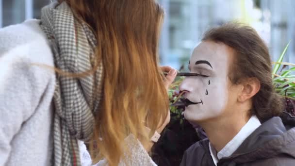 Fille peinture visage à jeune homme mime avec crayon noir — Video