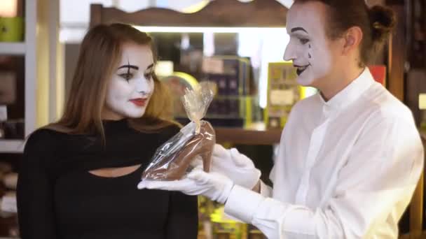 Glücklicher Mann, der seiner Freundin einen Schokoladenschuh schenkt. Zwei glückliche Pantomimen bei einem Date im Café — Stockvideo