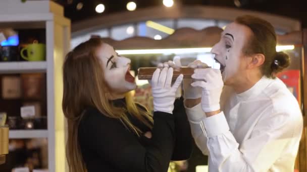 Two happy mimes with big chocolate bar in the cafe — Stock Video
