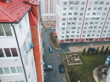 Endüstriyel tırmanışçı yeni bir binanın cephesini boyuyor.