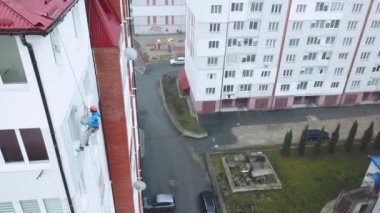 Endüstriyel tırmanışçı yeni bir binanın cephesini boyuyor.