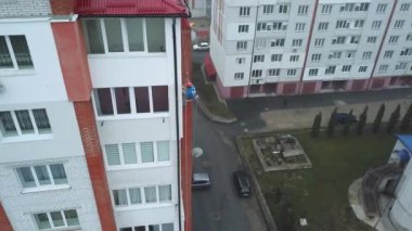 Endüstriyel tırmanışçı yeni bir binanın cephesini boyuyor.