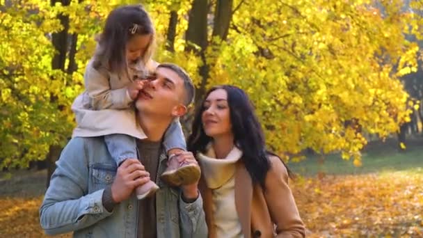 Dziecko na plecach ojca. Szczęśliwa rodzina w jesiennym parku. Spadek — Wideo stockowe