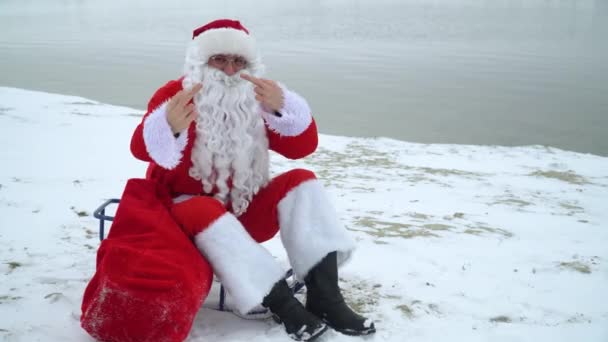 Dåliga jultomten visar dig långfingret på den snöiga stranden. — Stockvideo