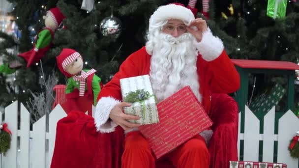 Papai Noel coloca um presente em um saco no empório. Papai Noel gestos OK para a câmera — Vídeo de Stock