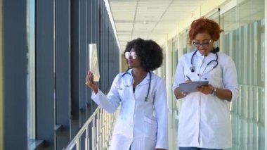 İki kadın Afro-Amerikalı doktor ciğerlerinin röntgenini çekiyorlar, içeride tutuyorlar. İki uzman göğsün şeffaf görüntüsünü kollarında tutuyor ve dikkatlice araştırıyor.