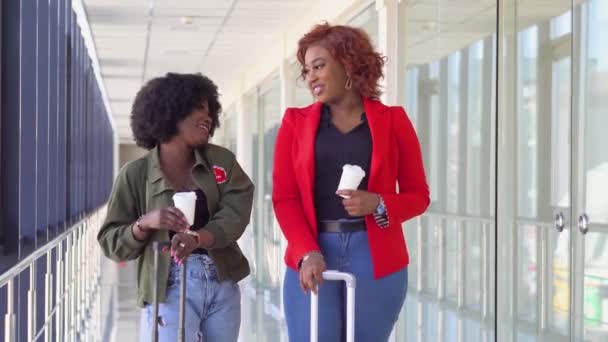 Dos amigas afroamericanas están esperando embarcar y salir en el aeropuerto. Chicas toman café en el aeropuerto — Vídeo de stock