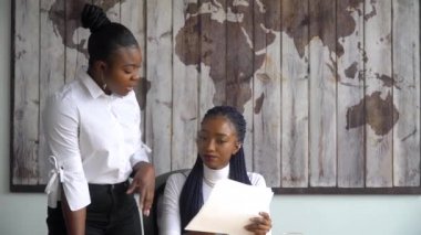 Güzel Afrikalı Amerikalı iş kadını, grafik ve istatistik içeren belgeler hakkında proje yöneticisine danışıyor.