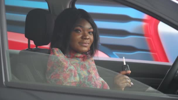 Heureuse femme afro-américaine montrant la clé de sa nouvelle voiture. Entreprise automobile, vente de voitures, concept de technologie et de personnes — Video