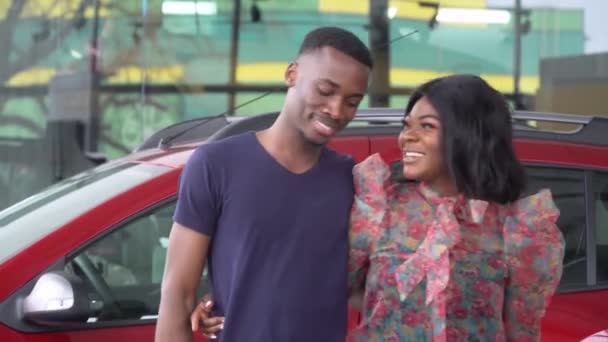 Casal afro-americano feliz abraçando perto de seu carro novo. Auto negócio, venda de carros, tecnologia e conceito de pessoas — Vídeo de Stock