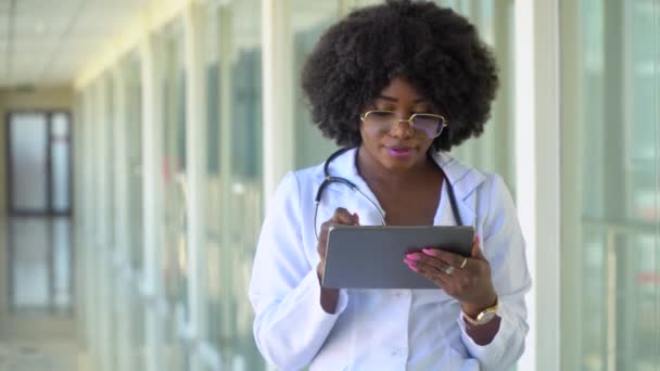 En el hospital, el médico usa tableta. Nueva instalación médica moderna totalmente funcional. Primer plano del médico afroamericano en el hospital — Vídeos de Stock