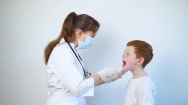 Küçük bir çocuğun boğazını kontrol eden bir çocuk doktoru. Grip salgını, ev doktoru servisi.