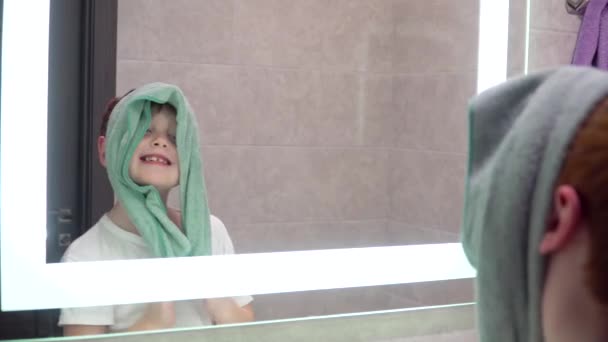 Funny red-haired boy looks in the bathroom mirror — Stock Video