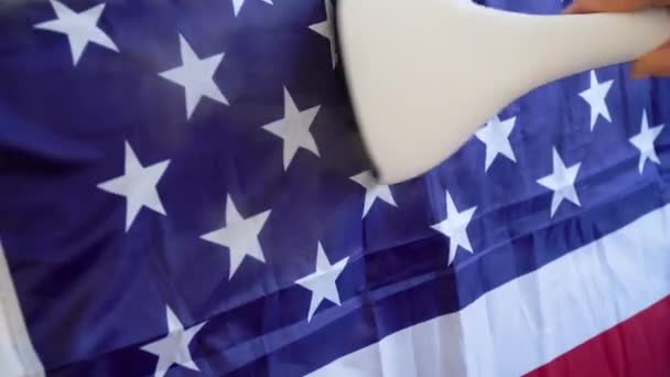 Uma mulher acaricia a bandeira dos EUA com um ferro a vapor. Preparativos para o Dia dos Veteranos dos EUA — Vídeo de Stock