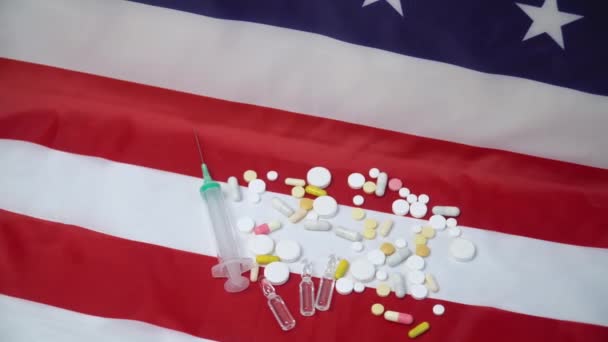 Blandade tabletter och spruta på amerikansk flagga. USA:s hälso- och sjukvård — Stockvideo
