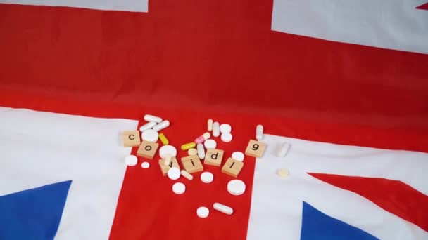 Gemengde pillen op Britse vlag met de inscriptie covid 19. Coronavirus in het Verenigd Koninkrijk. Overwinning op het coronavirus — Stockvideo