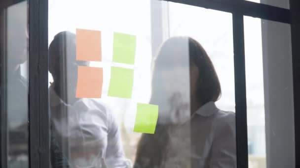 Unternehmen multiethnischen Menschen mit klebrigen Notizen, Lösungsstrategie auf Glas Whiteboard. Teamleiter Männchen zeigt Lösung für Projekttermin in Büro-Sitzung — Stockvideo