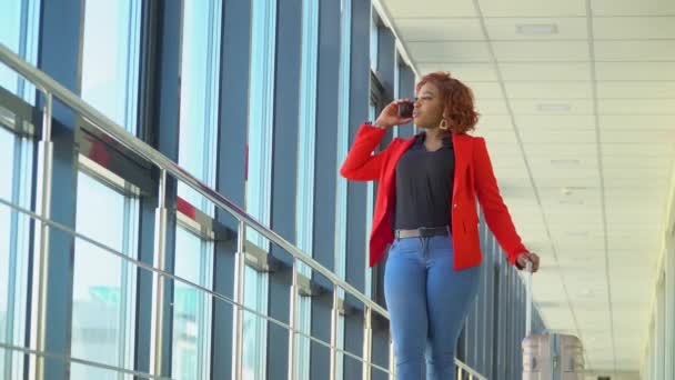 Afrikaans Amerikaans meisje wachten om te boarden en vertrekken op de luchthaven en praten aan de telefoon — Stockvideo