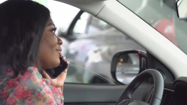 Αφροαμερικανή επιχειρηματίας που μιλάει στο τηλέφωνο ενώ κάθεται σε ένα αυτοκίνητο. Το αυτοκίνητο είναι λευκό. — Αρχείο Βίντεο