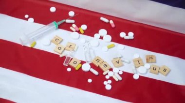 Birleşik Devletler bayrağında Coronavirus yazısıyla karıştırılmış haplar ve şırınga. ABD 'de Coronavirus. Coronavirus 'a karşı zafer. Covid-19 aşısı
