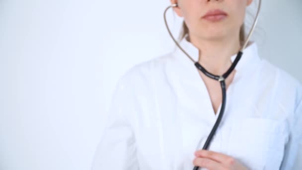 Портрет молодой женщины-врача в белом халате со стетоскопом на белом фоне в больнице. Прием пациента с пневмонией — стоковое видео