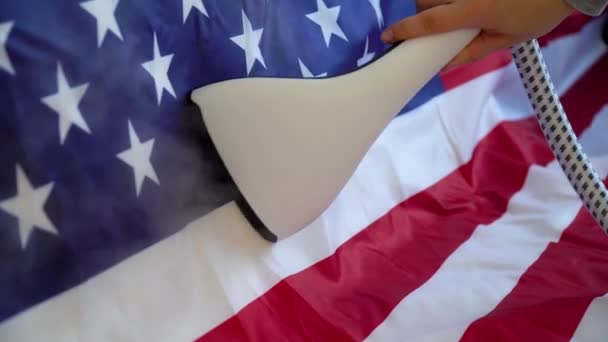 A woman strokes the US flag with a steam iron. US Independence Day Preparations Stock Footage
