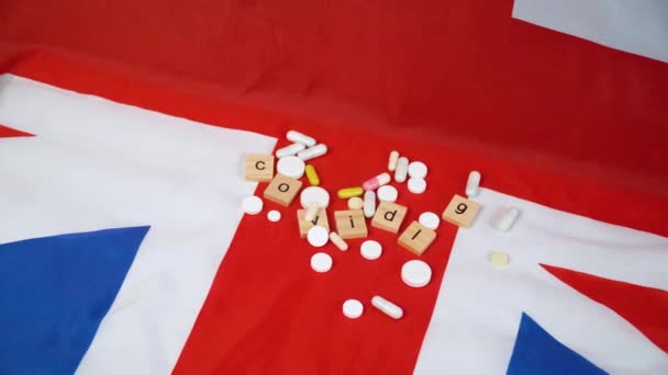 碑文と英国のフラグ上の混合錠剤covid 19.イギリスのコロナウイルス。コロナウイルスの勝利 — ストック動画