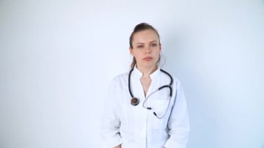 Hastanenin beyaz arka planında steteskopu olan beyaz önlüklü genç bir doktorun portresi.