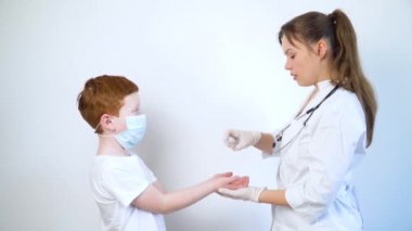 Bir kadın doktor, küçük bir çocuğun ellerini antiseptik spreyle dezenfekte ediyor. Yakın plan.