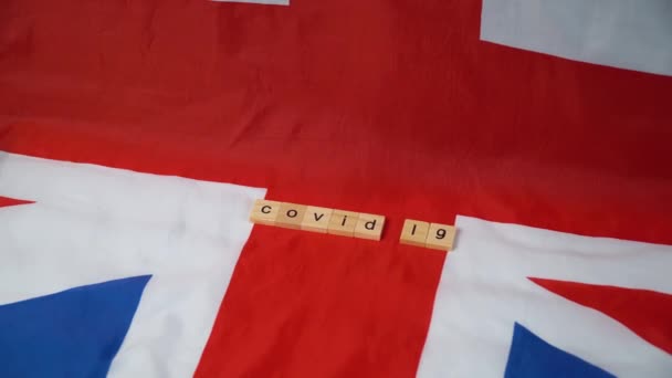 Brittisk flagga med inskriptionen covid 19. Coronavirus i Förenade kungariket — Stockvideo