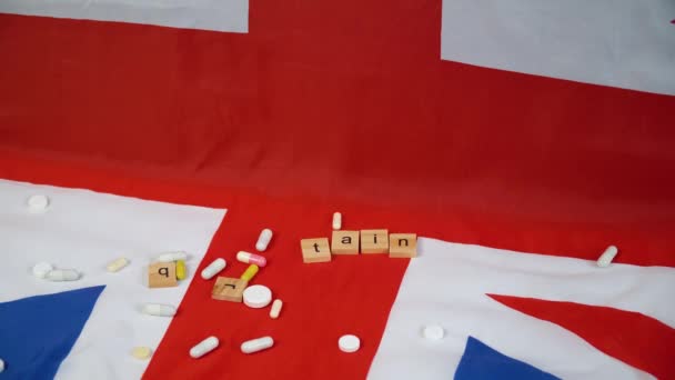Smíšené pilulky padající na britskou vlajku s nápisem Británie. Zpětná rychlost — Stock video