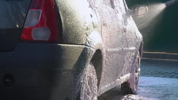Samoobsługowa myjnia. Mężczyzna myje samochód wysokociśnieniowym sprzętem — Wideo stockowe