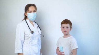 Kadın doktor, çocuk doktoru ve hasta çocuk kameraya bakın ve sınıfa gösterin.