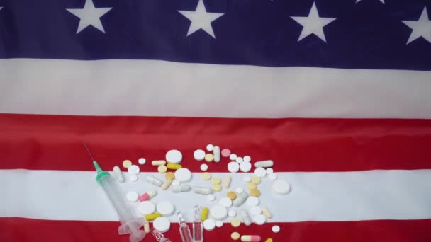 Comprimidos mistos e seringa na bandeira dos EUA. Saúde dos EUA. Coronavírus nos EUA — Vídeo de Stock