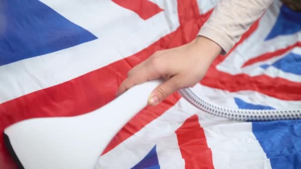 Vrouw strijkt Britse vlag met stoom strijkijzer. Voorbereiding van de nationale feestdag — Stockvideo